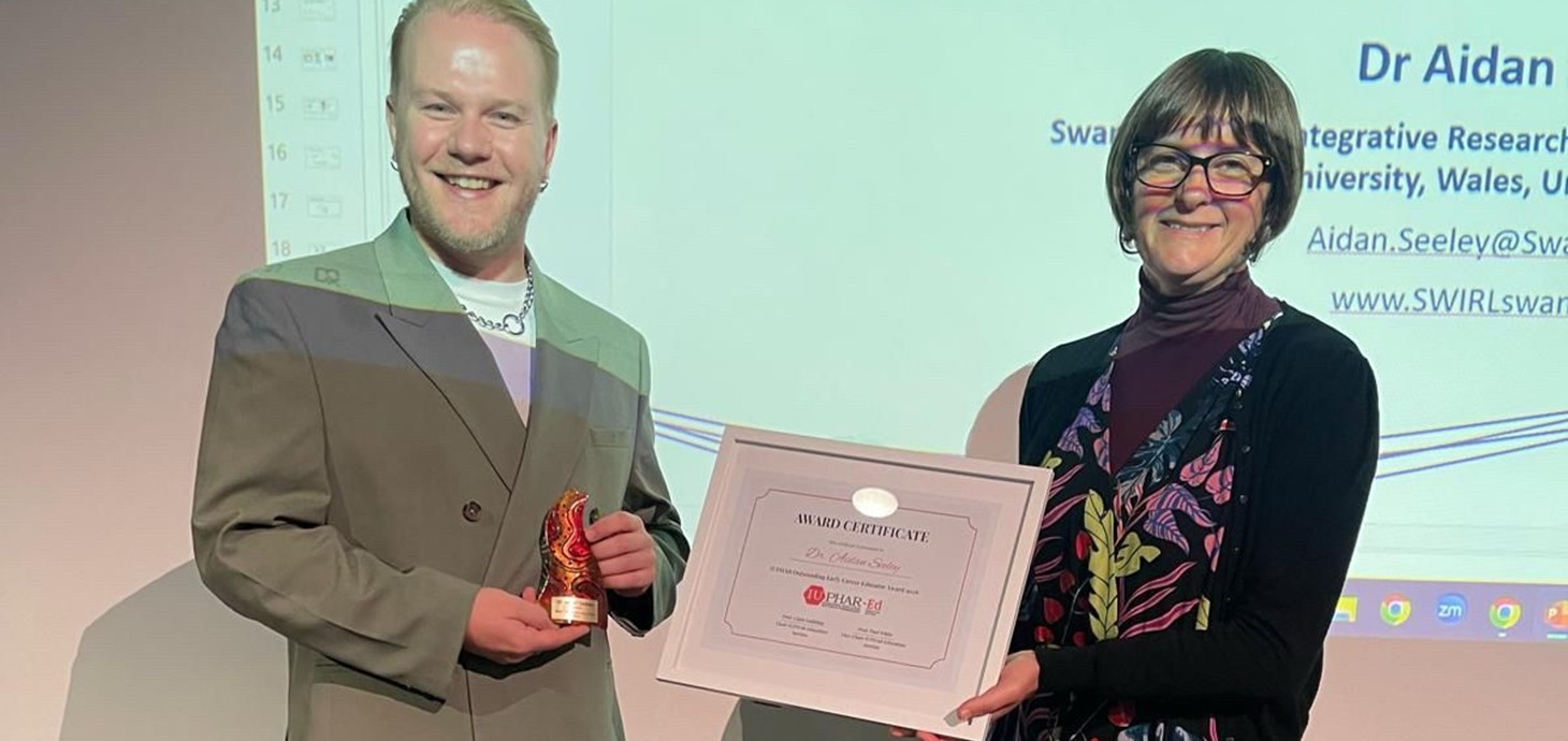 Man holding trophy alongside woman holding certificate.