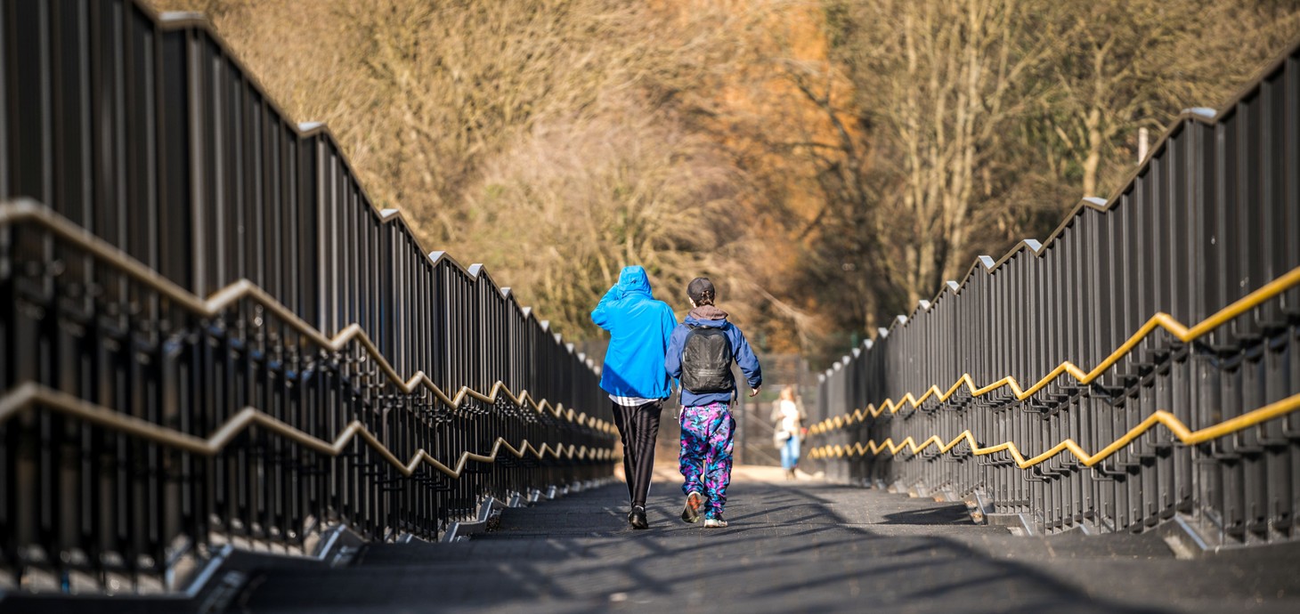 Two children walking away from camera along a bridge.