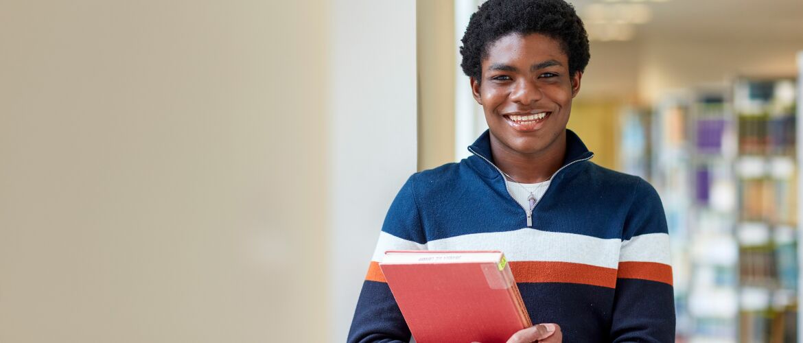 A student holding a book in the library 