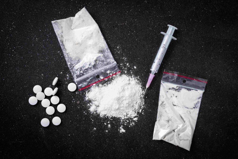 pills, white powder and syringe on a black background