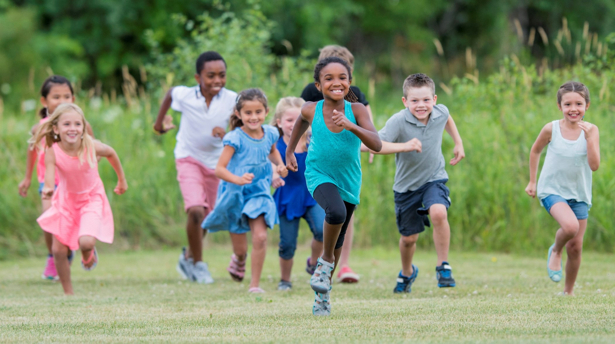 a group of children running on a green field