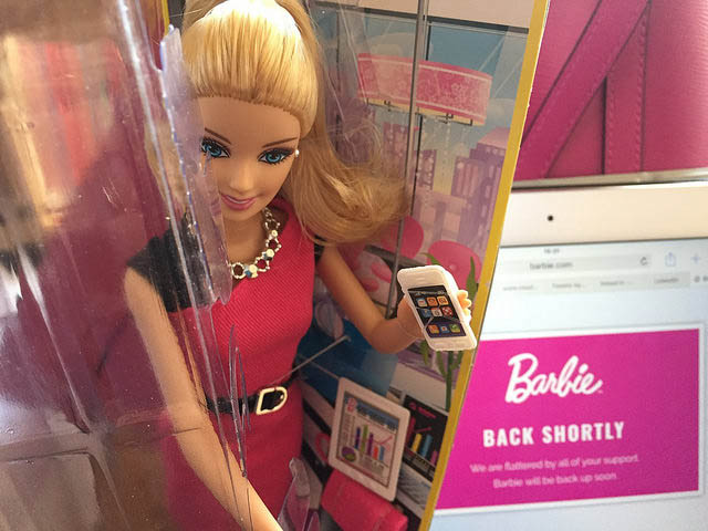 A Barbie doll in a box, holding a phone 