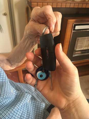 The hand of an older person handing car keys to the hand of a younger person
