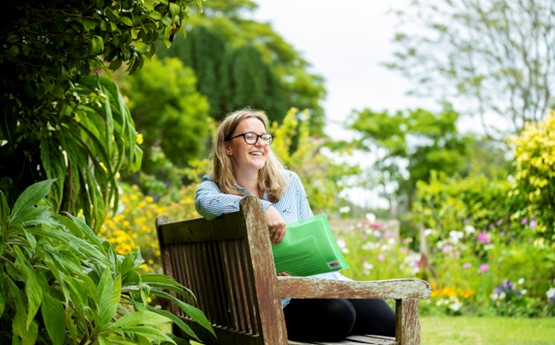 Woman sitting on bench in a lush, green area