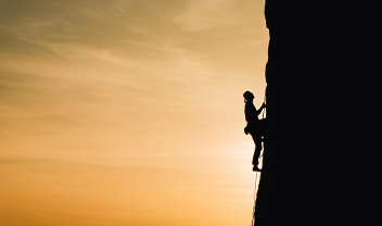A silhouette of someone climbing a cliff