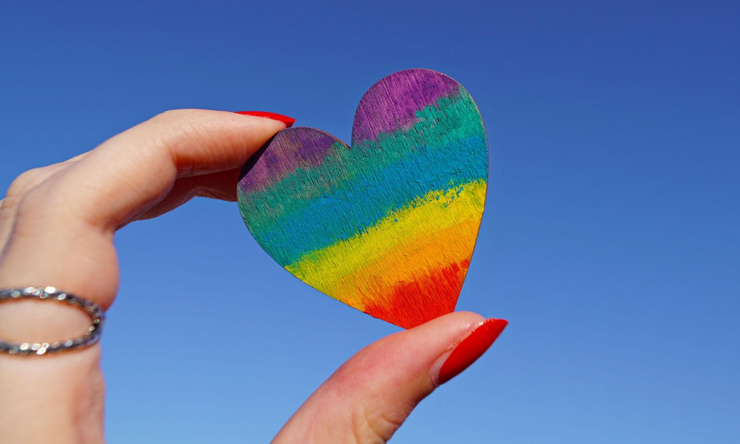 hand holding painted rainbow heart