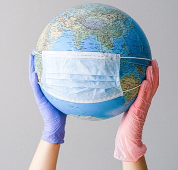 Globe held in hands with medical mask