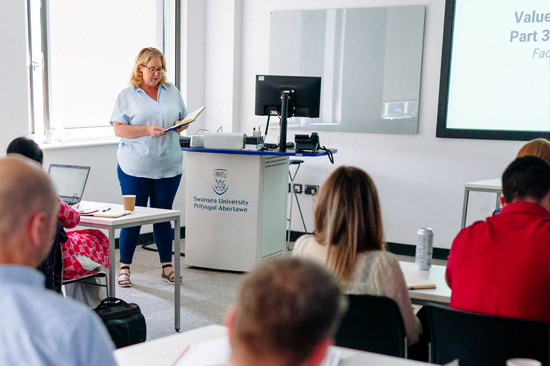 A female teacher lecturing to a class of people