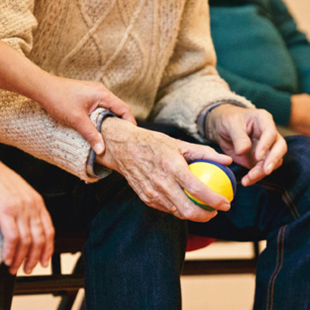 an elderly person holds a stress ball