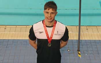 An image of Swansea student and Sport Swansea swimming scholar Lewis Fraser proudly wearing medal
