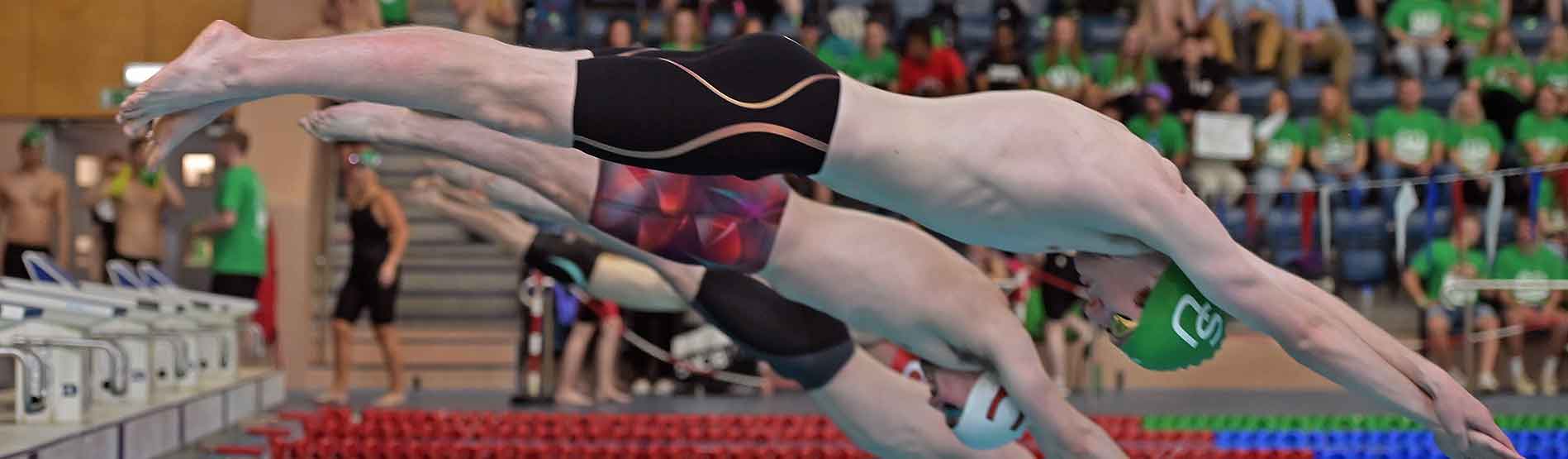Swimmers diving into Wales National Pool during swimming competition