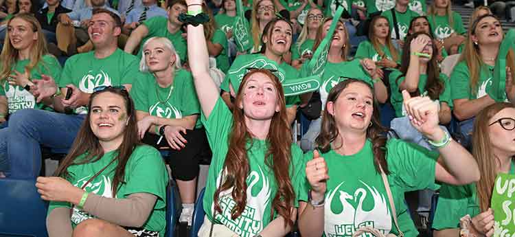 Swansea University students dressed in green t shirts in stands at Wales National Pool
