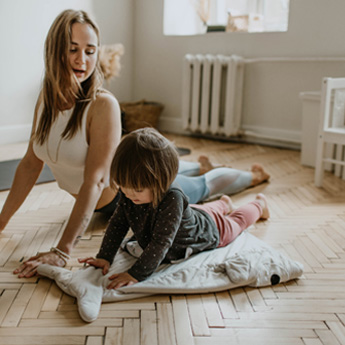 A mum and her daughter practice yoga on the floor