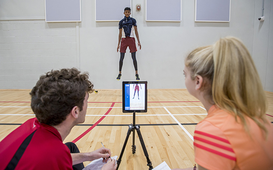 students in sports hall measuring jumps