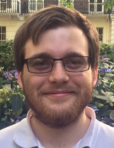 Picture of a man wearing glasses against a natural background.