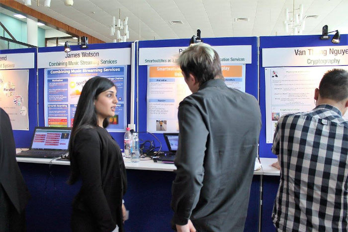 Picture of project Fair student talking to lecturer in front of a poster board