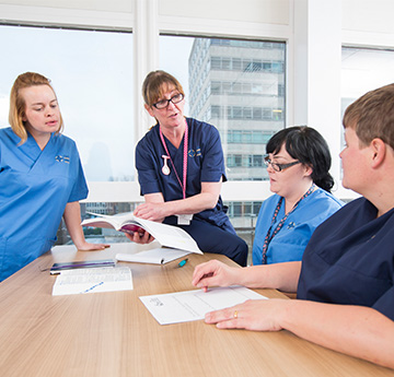 A nursing academic and students talking around a table