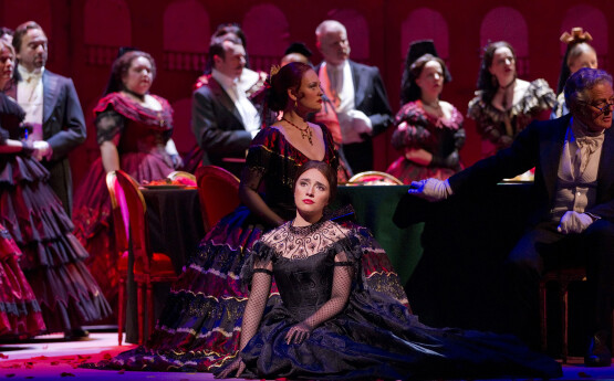 A woman singing on stage with an orchestra behind her