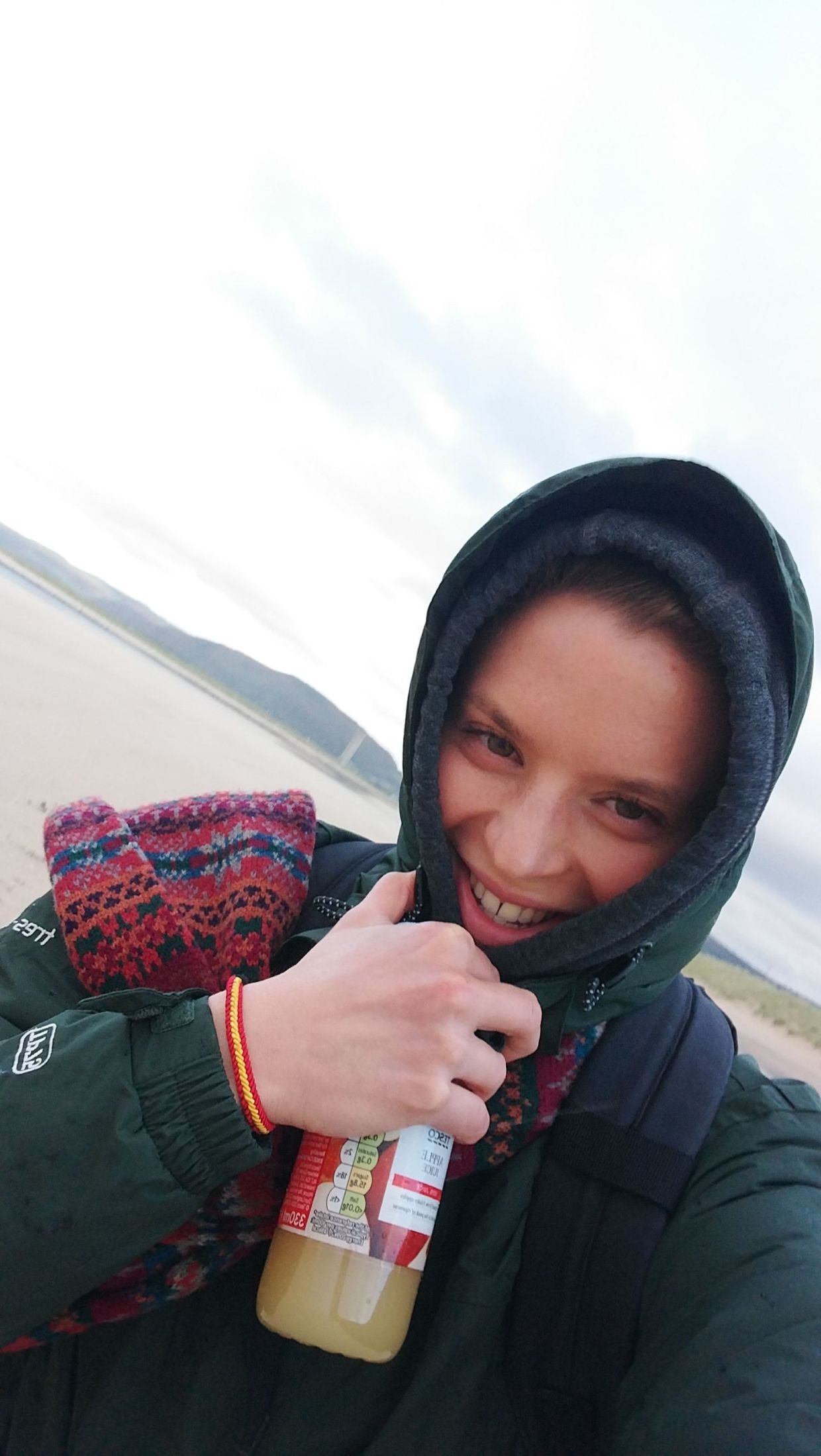 Student on Swansea beach in a scarf and thick coat.