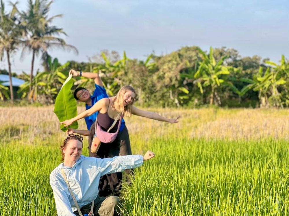 Three students in a row in green field