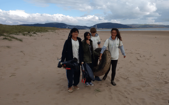 Four volunteers on the beach taking part in a litter pick