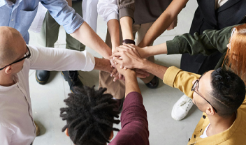 Students stood in a circle with their hands stacked on top of one another