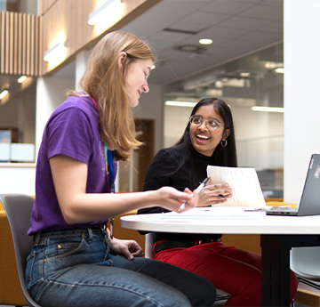 two laughing students studying in the library