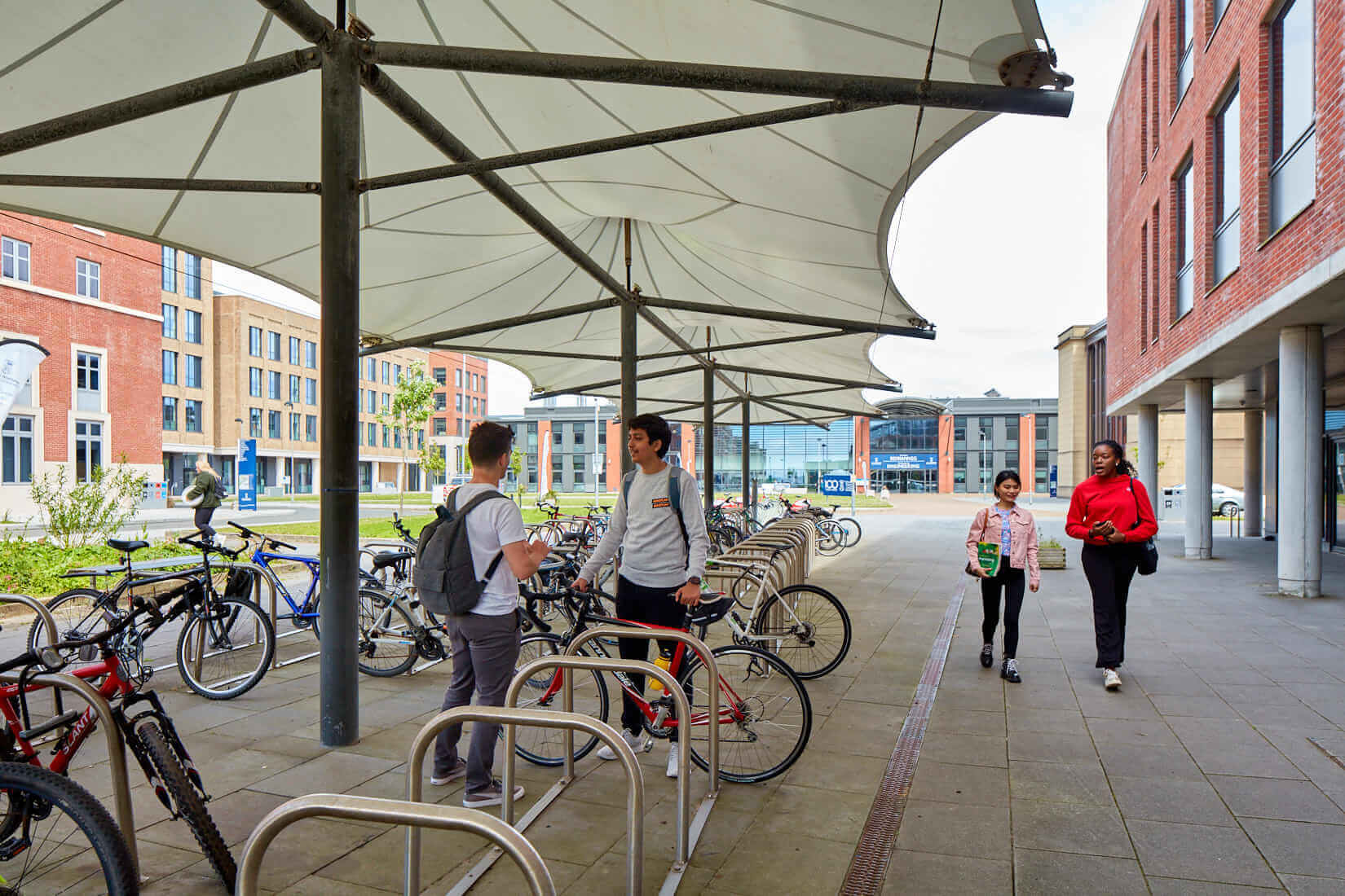 Two students chatting at a cycle rack at the Bay Campus