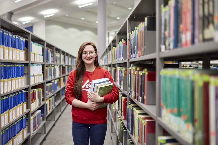 Student in library holding books