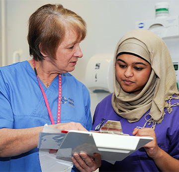 Student and Nursing lecturer looking at patient records
