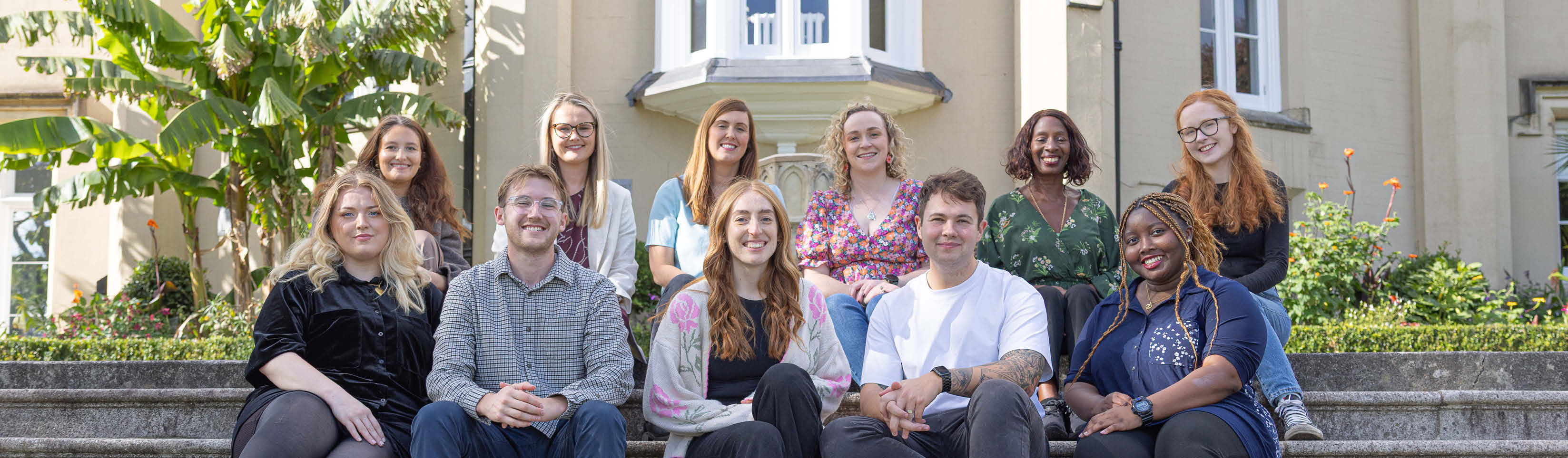Staff sitting on steps outside the Abbey on Singleton Campus