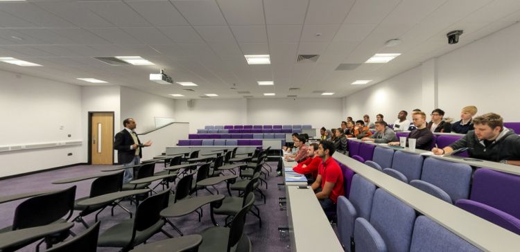 Lecture theatre with a presenter at the front and students seated in rows