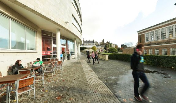 People walking past glass-fronted building with coloured panels
