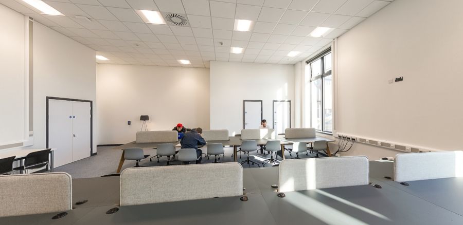 Students studying at desks in a bright open-plan study zone with group seating