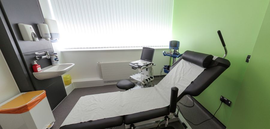 Examination room with medical couch, sink, and diagnostic equipment