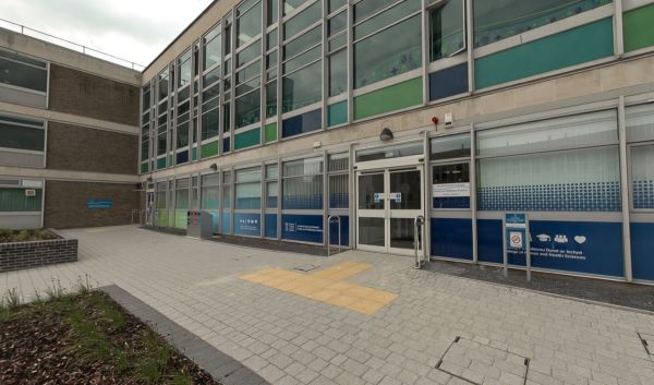 Exterior of a campus building with paved walkway and flower beds