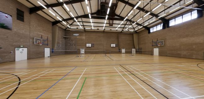 Indoor sports hall with marked courts, basketball hoops, and nets