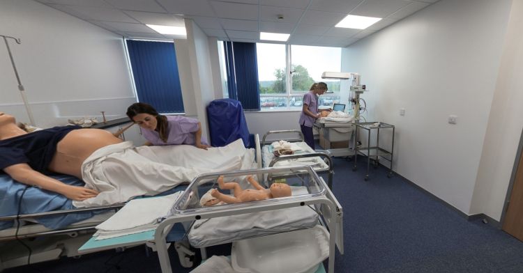Midwifery practice room with birthing simulator, infant cot and equipment