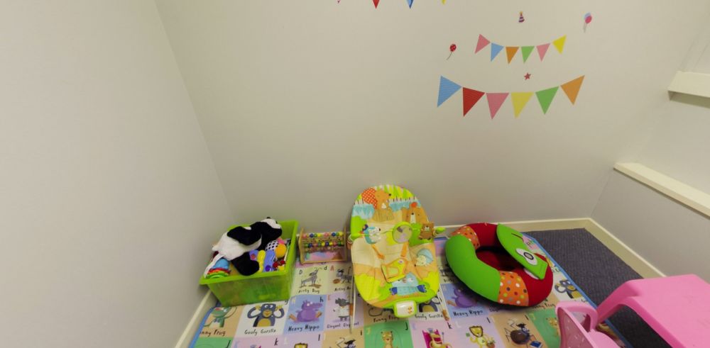 Children's play area with toys, seating and colourful floor mat