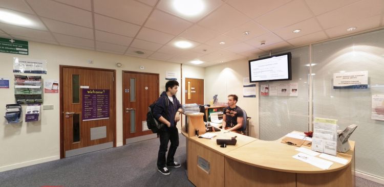 Student Services reception desk with staff member and visitor