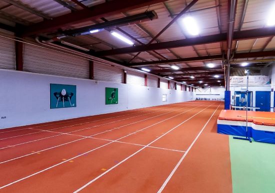 Indoor running track beside green training area in a sports hall
