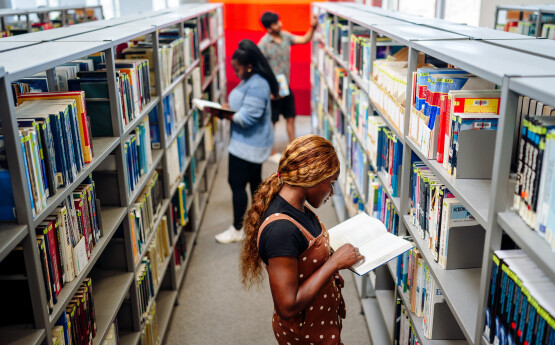 students browsing books on library shelves