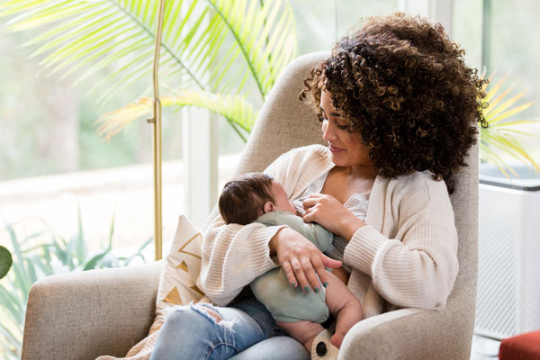 Woman breastfeeding child on a sofa